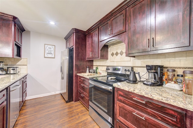 kitchen featuring tasteful backsplash, appliances with stainless steel finishes, dark hardwood / wood-style flooring, and light stone counters