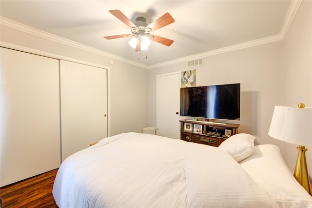 bedroom with ceiling fan, crown molding, dark hardwood / wood-style floors, and a closet