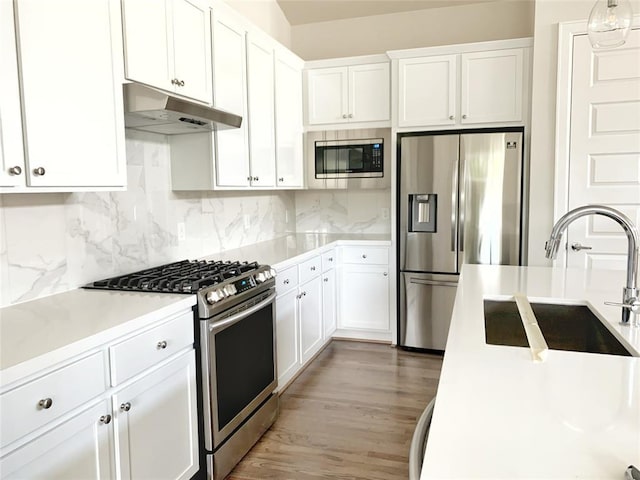 kitchen with appliances with stainless steel finishes, white cabinetry, hanging light fixtures, and sink