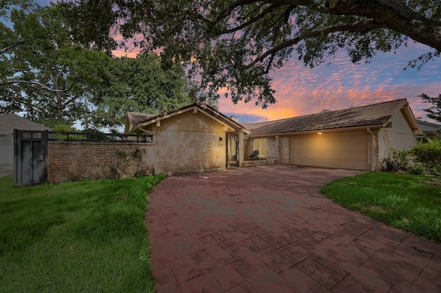 ranch-style home featuring a lawn and a garage