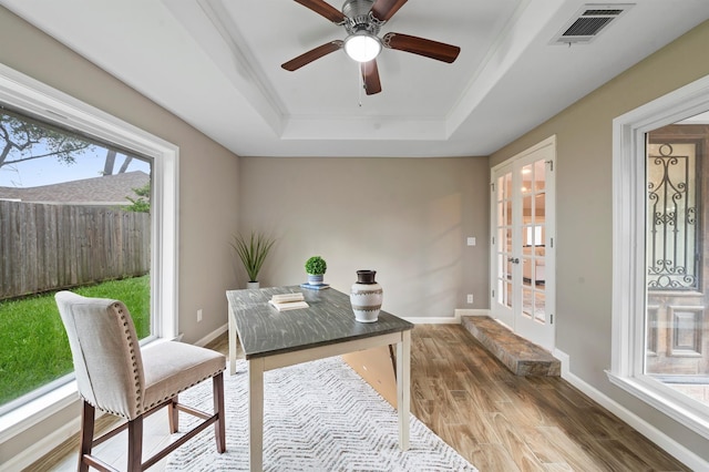 office space featuring ceiling fan, a raised ceiling, wood-type flooring, crown molding, and french doors