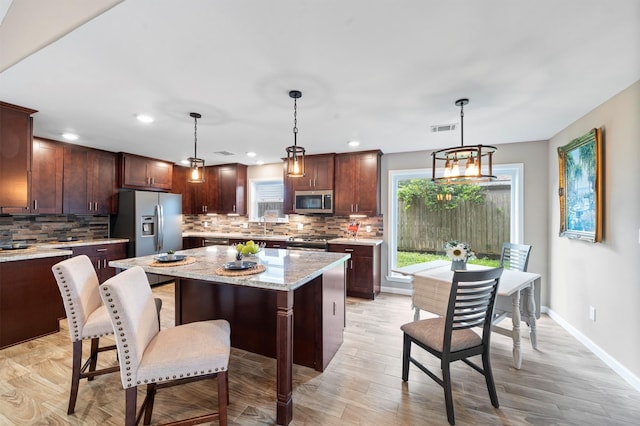 kitchen with decorative light fixtures, tasteful backsplash, stainless steel appliances, and a kitchen island