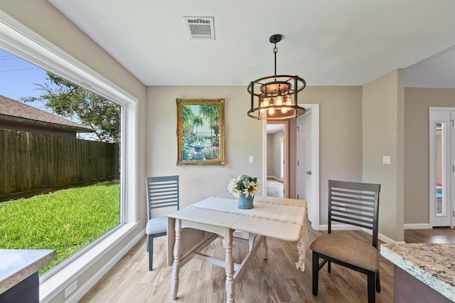 dining area with a wealth of natural light, a chandelier, and light hardwood / wood-style flooring