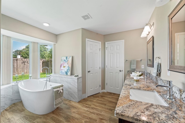 bathroom with a bath, wood-type flooring, and vanity