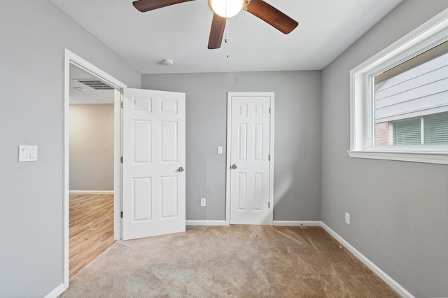 unfurnished bedroom featuring ceiling fan, light colored carpet, and a closet