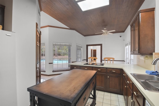 kitchen with ceiling fan, kitchen peninsula, sink, light tile patterned flooring, and wood ceiling