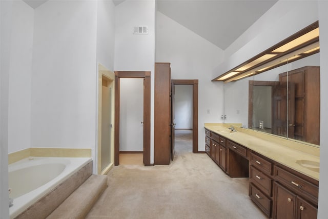 bathroom with tiled tub, vanity, and high vaulted ceiling