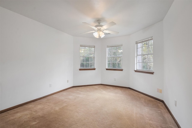 carpeted spare room featuring ceiling fan and a healthy amount of sunlight