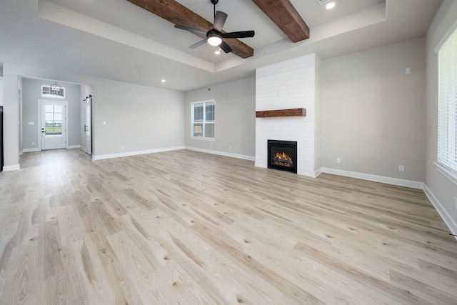 unfurnished living room featuring ceiling fan, light hardwood / wood-style flooring, a raised ceiling, and a fireplace