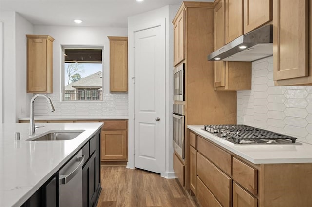 7462 Cattail Falls Ln, Porter, TX 77365 - kitchen featuring a sink, stainless steel appliances, under cabinet range hood, light countertops, and decorative backsplash