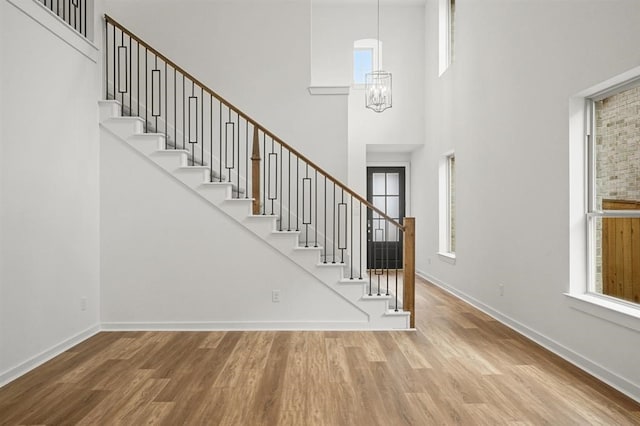 7462 Cattail Falls Ln, Porter, TX 77365 - stairway with wood finished floors, a high ceiling, baseboards, and a chandelier
