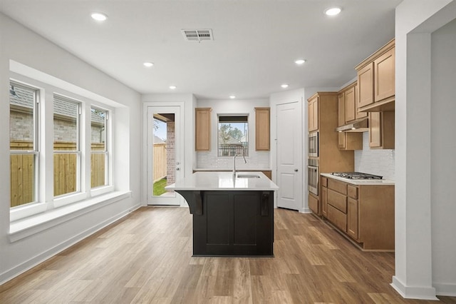 7462 Cattail Falls Ln, Porter, TX 77365 - kitchen with stainless steel appliances, a sink, under cabinet range hood, light countertops, and decorative backsplash