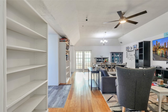 living room with vaulted ceiling, ceiling fan with notable chandelier, and hardwood / wood-style floors