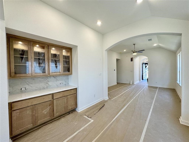 interior space with lofted ceiling, decorative backsplash, and ceiling fan