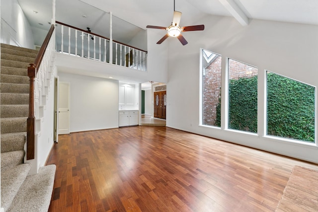 unfurnished living room with hardwood / wood-style flooring, ceiling fan, high vaulted ceiling, and beam ceiling