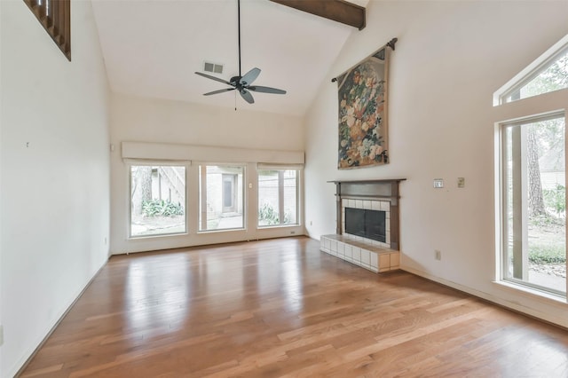 unfurnished living room with light hardwood / wood-style flooring, beamed ceiling, high vaulted ceiling, ceiling fan, and a tile fireplace