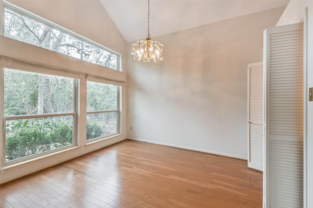 interior space with light wood-type flooring, vaulted ceiling, and a notable chandelier