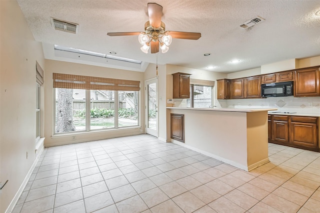 kitchen featuring a textured ceiling, lofted ceiling, kitchen peninsula, light tile patterned flooring, and ceiling fan