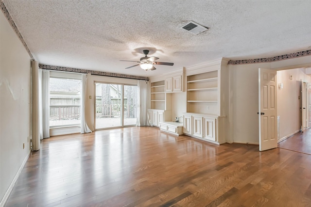 unfurnished living room featuring ceiling fan, hardwood / wood-style floors, and a textured ceiling