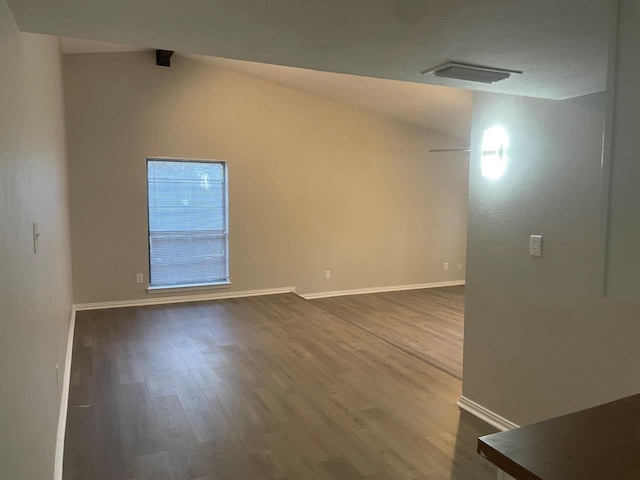 empty room with wood-type flooring and lofted ceiling