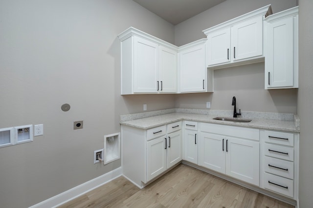 kitchen with light stone countertops, sink, white cabinetry, and light hardwood / wood-style flooring