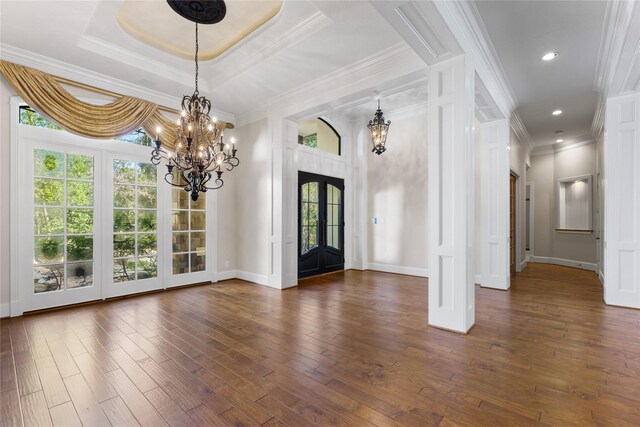 entrance foyer with a tray ceiling, ornamental molding, french doors, dark hardwood / wood-style flooring, and a chandelier