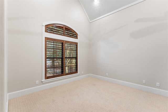 carpeted empty room featuring high vaulted ceiling and crown molding