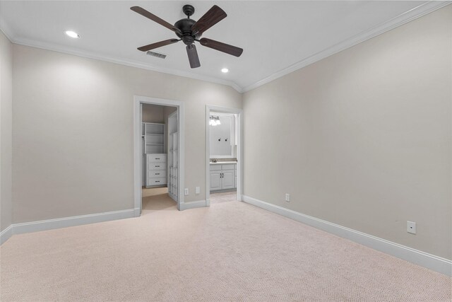 unfurnished bedroom with a spacious closet, ensuite bathroom, ceiling fan, a closet, and crown molding