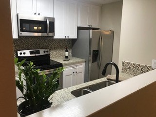 kitchen featuring sink, white cabinetry, appliances with stainless steel finishes, and tasteful backsplash