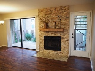 unfurnished living room with a fireplace, plenty of natural light, a notable chandelier, and dark hardwood / wood-style floors