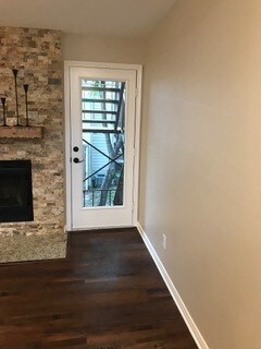 doorway with dark hardwood / wood-style flooring and a stone fireplace