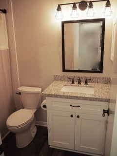 bathroom featuring toilet, vanity, and hardwood / wood-style floors