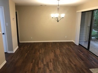 spare room featuring dark hardwood / wood-style flooring and an inviting chandelier