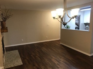 unfurnished dining area with a notable chandelier and dark hardwood / wood-style floors