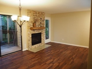 unfurnished living room with plenty of natural light, a high end fireplace, dark hardwood / wood-style floors, and a notable chandelier