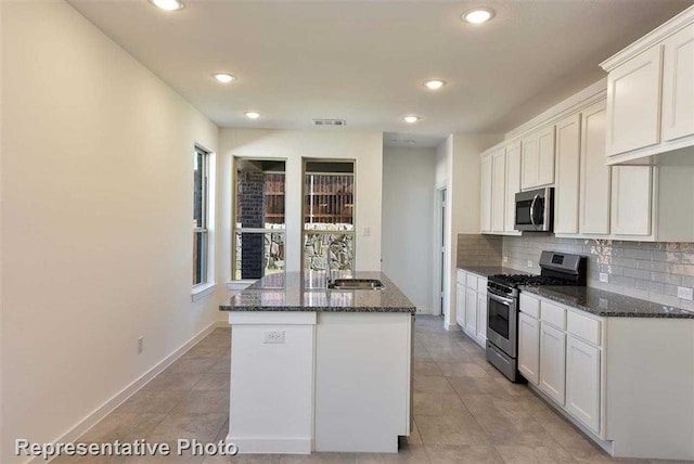 kitchen with stainless steel appliances, decorative backsplash, dark stone countertops, white cabinets, and sink