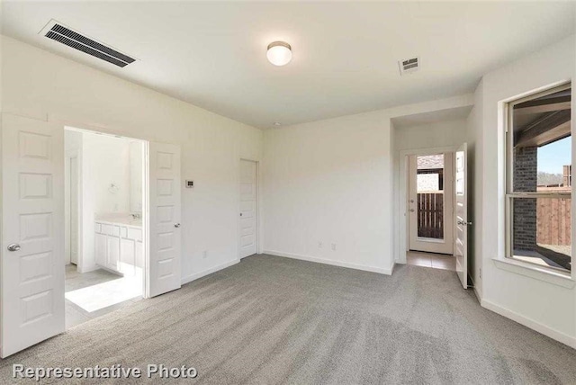 unfurnished bedroom with light colored carpet and connected bathroom