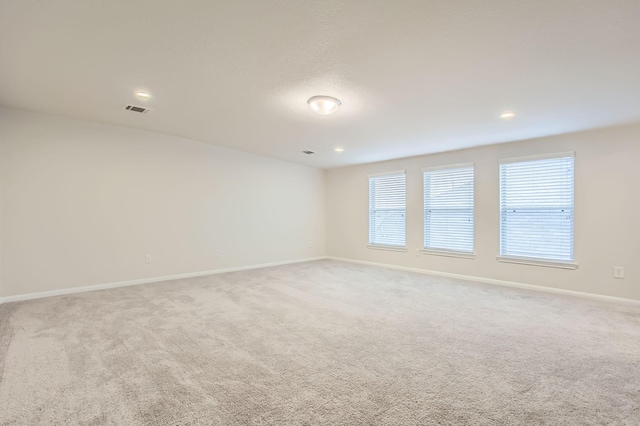 empty room featuring light colored carpet and plenty of natural light