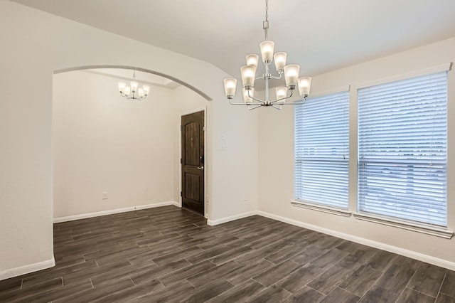 spare room featuring dark hardwood / wood-style floors, a notable chandelier, and vaulted ceiling