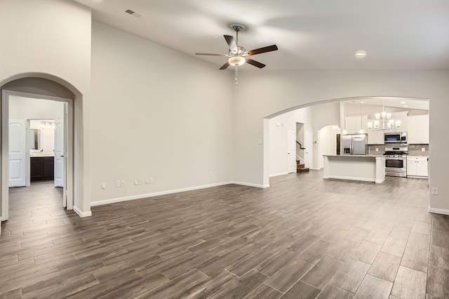 7535 Cypress Pin Oak Dr, Cypress, TX 77433 - unfurnished living room with dark wood-style floors, lofted ceiling, ceiling fan with notable chandelier, visible vents, and arched walkways