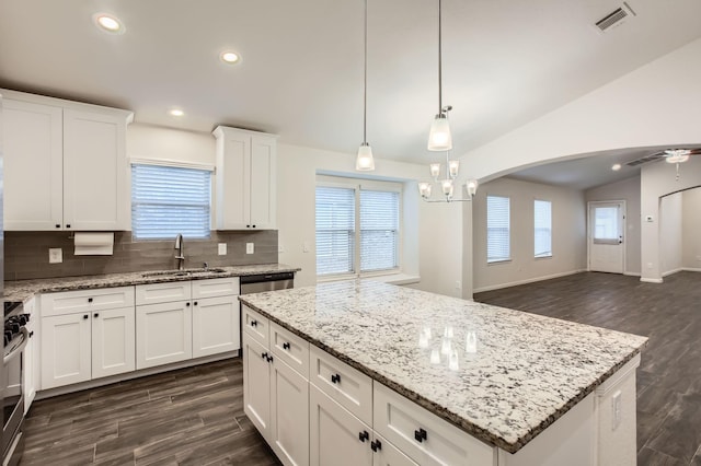 kitchen with vaulted ceiling, a kitchen island, pendant lighting, white cabinets, and sink