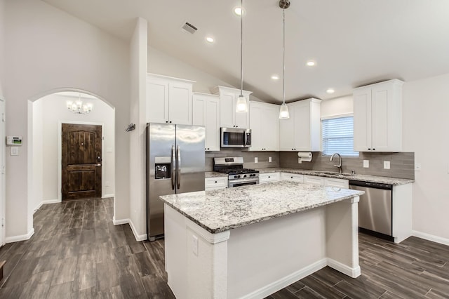 kitchen with pendant lighting, white cabinets, a kitchen island, stainless steel appliances, and vaulted ceiling