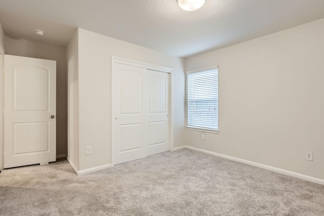 unfurnished bedroom featuring light carpet, a closet, and a textured ceiling