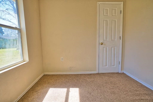 unfurnished room with carpet flooring and baseboards