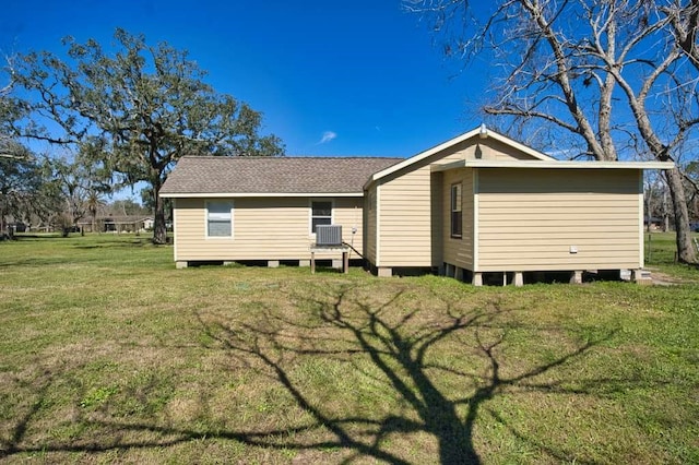 back of house featuring central air condition unit, a shingled roof, and a yard