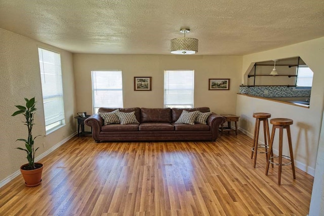 living area with a textured ceiling, baseboards, and wood finished floors