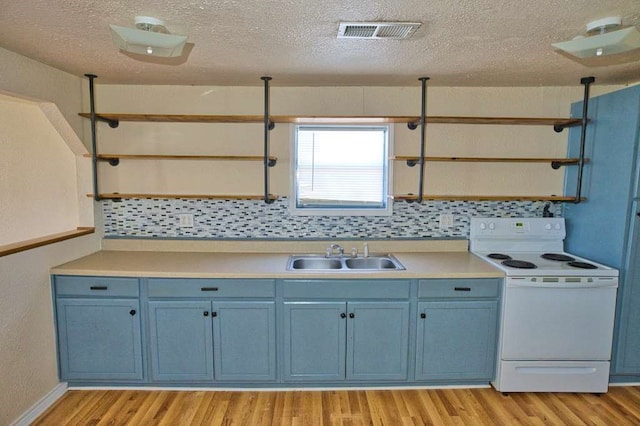 kitchen featuring electric range, visible vents, blue cabinetry, open shelves, and a sink