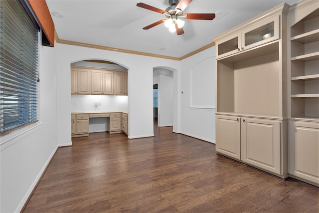 unfurnished living room featuring built in desk, ceiling fan, dark hardwood / wood-style flooring, and crown molding