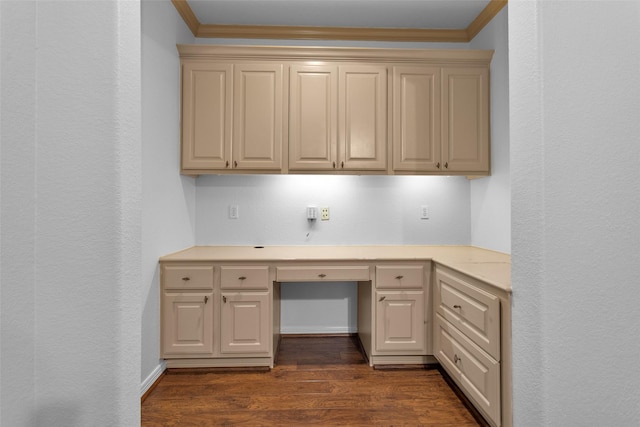 unfurnished office featuring built in desk, dark hardwood / wood-style floors, and ornamental molding