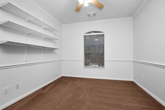 empty room with ceiling fan, crown molding, and dark colored carpet